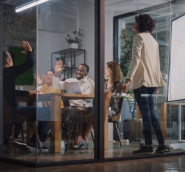 Project Manager Makes a Presentation for a Young Diverse Creative Team in Meeting Room in an Agency. Colleagues Sit Behind Conference Table and Discuss Business Development, User Interface and Design.
