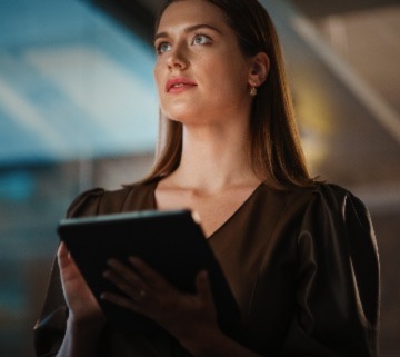 Portrait of a Young Creative Caucasian Female with Dark Hair Using a Tablet Computer in Evening Dress or Blouse. Beautiful Diverse Independent Woman is Browsing Internet and Chatting in Messenger.